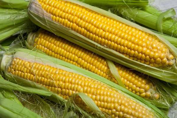 Taze mısır koçanı üzerinde rustik ahşap masa, yakın çekim. Tatlı Mısır kulakları arka plan