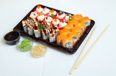 Japon yemekleri plastik kutuda yuvarlanıyor. Sushi plastik bir paketin içinde, beyaz bir arka planda izole edilmiş. Paket veya suşi servisi için suşi..