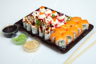 Japon yemekleri plastik kutuda yuvarlanıyor. Sushi plastik bir paketin içinde, beyaz bir arka planda izole edilmiş. Paket veya suşi servisi için suşi..