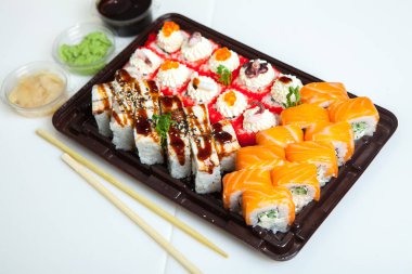 Japon yemekleri plastik kutuda yuvarlanıyor. Sushi plastik bir paketin içinde, beyaz bir arka planda izole edilmiş. Paket veya suşi servisi için suşi..