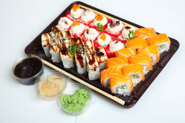 Japon yemekleri plastik kutuda yuvarlanıyor. Sushi plastik bir paketin içinde, beyaz bir arka planda izole edilmiş. Paket veya suşi servisi için suşi..