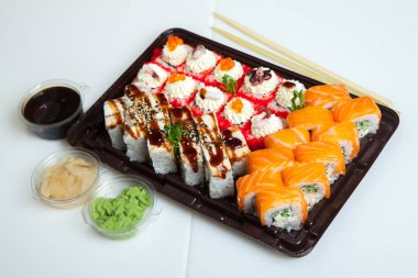 Japon yemekleri plastik kutuda yuvarlanıyor. Sushi plastik bir paketin içinde, beyaz bir arka planda izole edilmiş. Paket veya suşi servisi için suşi..