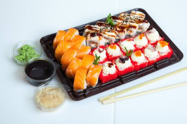 Japon yemekleri plastik kutuda yuvarlanıyor. Sushi plastik bir paketin içinde, beyaz bir arka planda izole edilmiş. Paket veya suşi servisi için suşi..