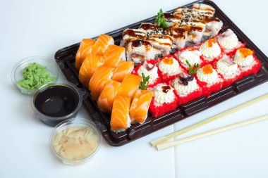 Japon yemekleri plastik kutuda yuvarlanıyor. Sushi plastik bir paketin içinde, beyaz bir arka planda izole edilmiş. Paket veya suşi servisi için suşi..