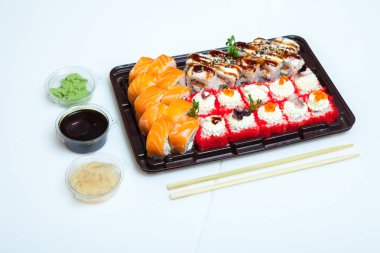Japon yemekleri plastik kutuda yuvarlanıyor. Sushi plastik bir paketin içinde, beyaz bir arka planda izole edilmiş. Paket veya suşi servisi için suşi..