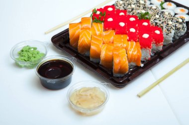 Japon yemekleri plastik kutuda yuvarlanıyor. Sushi plastik bir paketin içinde, beyaz bir arka planda izole edilmiş. Paket veya suşi servisi için suşi..