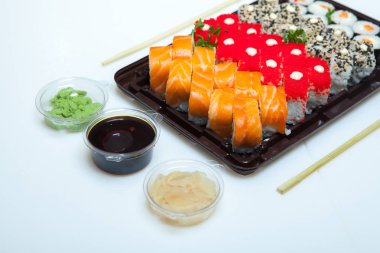 Japon yemekleri plastik kutuda yuvarlanıyor. Sushi plastik bir paketin içinde, beyaz bir arka planda izole edilmiş. Paket veya suşi servisi için suşi..