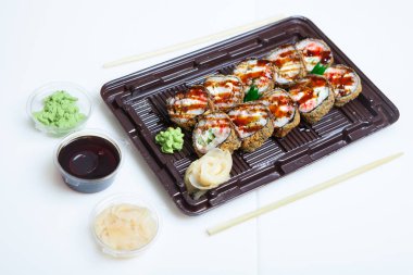 Japon yemekleri plastik kutuda yuvarlanıyor. Sushi plastik bir paketin içinde, beyaz bir arka planda izole edilmiş. Paket veya suşi servisi için suşi..