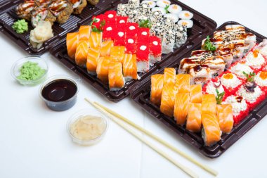 Japon yemekleri plastik kutuda yuvarlanıyor. Sushi plastik bir paketin içinde, beyaz bir arka planda izole edilmiş. Paket veya suşi servisi için suşi..
