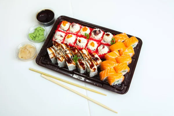 Japanese food rolls in plastic box. Sushi set in a plastic package close up isolated on a white background. Sushi for take away or sushi delivery.