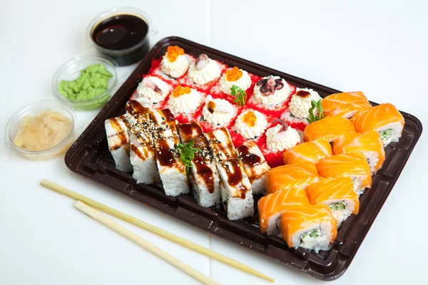 Japanese food rolls in plastic box. Sushi set in a plastic package close up isolated on a white background. Sushi for take away or sushi delivery.