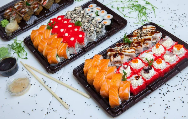 Japanese food rolls in plastic box. Sushi set in a plastic package close up isolated on a white background. Sushi for take away or sushi delivery.