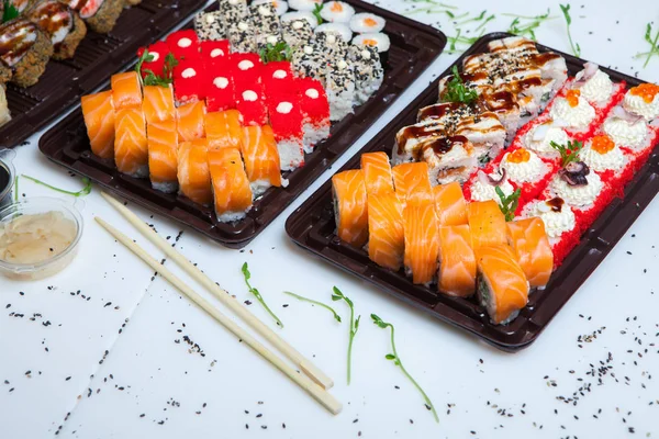 Japanese food rolls in plastic box. Sushi set in a plastic package close up isolated on a white background. Sushi for take away or sushi delivery.