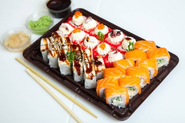 Japon yemekleri plastik kutuda yuvarlanıyor. Sushi plastik bir paketin içinde, beyaz bir arka planda izole edilmiş. Paket veya suşi servisi için suşi..