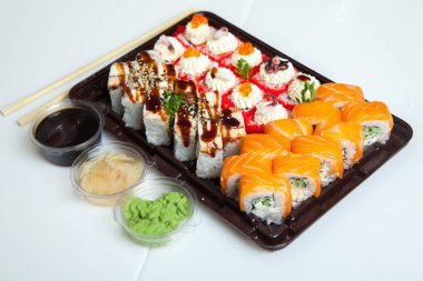 Japon yemekleri plastik kutuda yuvarlanıyor. Sushi plastik bir paketin içinde, beyaz bir arka planda izole edilmiş. Paket veya suşi servisi için suşi..