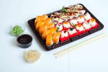 Japon yemekleri plastik kutuda yuvarlanıyor. Sushi plastik bir paketin içinde, beyaz bir arka planda izole edilmiş. Paket veya suşi servisi için suşi..
