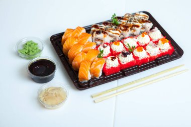 Japon yemekleri plastik kutuda yuvarlanıyor. Sushi plastik bir paketin içinde, beyaz bir arka planda izole edilmiş. Paket veya suşi servisi için suşi..