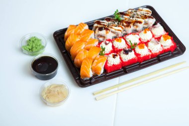 Japon yemekleri plastik kutuda yuvarlanıyor. Sushi plastik bir paketin içinde, beyaz bir arka planda izole edilmiş. Paket veya suşi servisi için suşi..