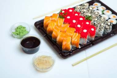Japon yemekleri plastik kutuda yuvarlanıyor. Sushi plastik bir paketin içinde, beyaz bir arka planda izole edilmiş. Paket veya suşi servisi için suşi..