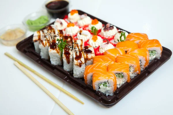 Japanese food rolls in plastic box. Sushi set in a plastic package close up isolated on a white background. Sushi for take away or sushi delivery.