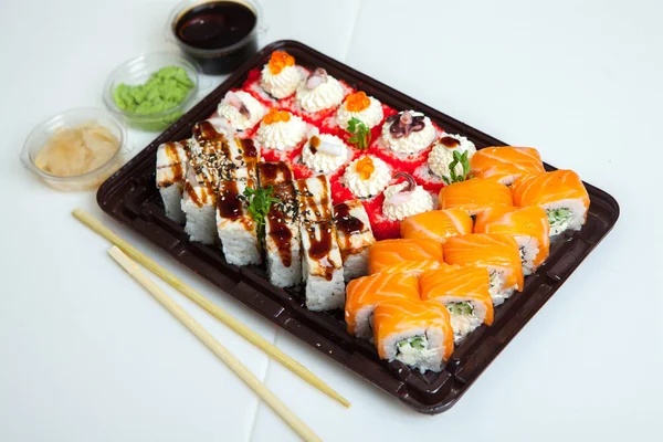 Japanese food rolls in plastic box. Sushi set in a plastic package close up isolated on a white background. Sushi for take away or sushi delivery.