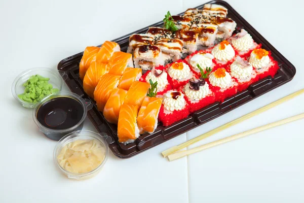 Japanese food rolls in plastic box. Sushi set in a plastic package close up isolated on a white background. Sushi for take away or sushi delivery.