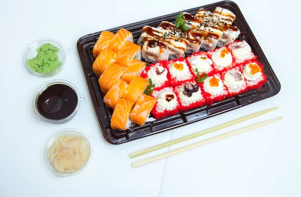 Japanese food rolls in plastic box. Sushi set in a plastic package close up isolated on a white background. Sushi for take away or sushi delivery.