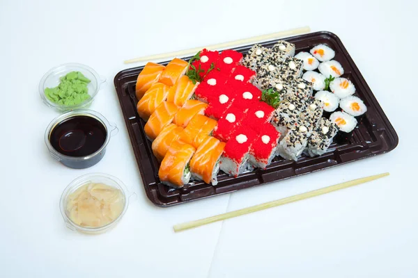 Japanese food rolls in plastic box. Sushi set in a plastic package close up isolated on a white background. Sushi for take away or sushi delivery.