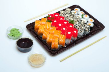 Japon yemekleri plastik kutuda yuvarlanıyor. Sushi plastik bir paketin içinde, beyaz bir arka planda izole edilmiş. Paket veya suşi servisi için suşi..