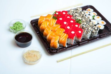 Japon yemekleri plastik kutuda yuvarlanıyor. Sushi plastik bir paketin içinde, beyaz bir arka planda izole edilmiş. Paket veya suşi servisi için suşi..