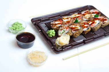 Japon yemekleri plastik kutuda yuvarlanıyor. Sushi plastik bir paketin içinde, beyaz bir arka planda izole edilmiş. Paket veya suşi servisi için suşi..