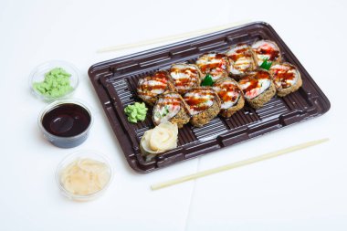 Japon yemekleri plastik kutuda yuvarlanıyor. Sushi plastik bir paketin içinde, beyaz bir arka planda izole edilmiş. Paket veya suşi servisi için suşi..