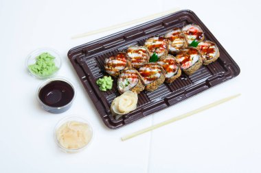 Japon yemekleri plastik kutuda yuvarlanıyor. Sushi plastik bir paketin içinde, beyaz bir arka planda izole edilmiş. Paket veya suşi servisi için suşi..