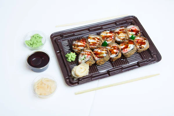 Japanese food rolls in plastic box. Sushi set in a plastic package close up isolated on a white background. Sushi for take away or sushi delivery.