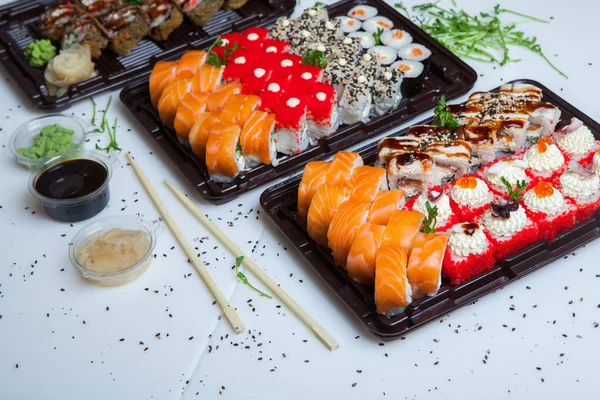 Japanese food rolls in plastic box. Sushi set in a plastic package close up isolated on a white background. Sushi for take away or sushi delivery.