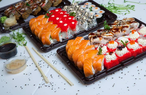 Japanese food rolls in plastic box. Sushi set in a plastic package close up isolated on a white background. Sushi for take away or sushi delivery.