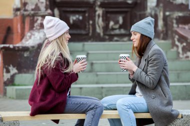 İki arkadaş rahatlatıcı ve kahve içme. Kahve molası. Gostylish yenilikçi kıza sokakta kahve içme kahve.