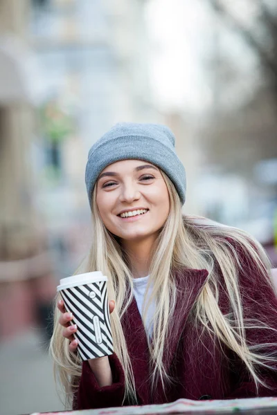 Beautiful woman holding paper coffee cup in the cityYoung stylish woman drinking coffee to go in a city street
