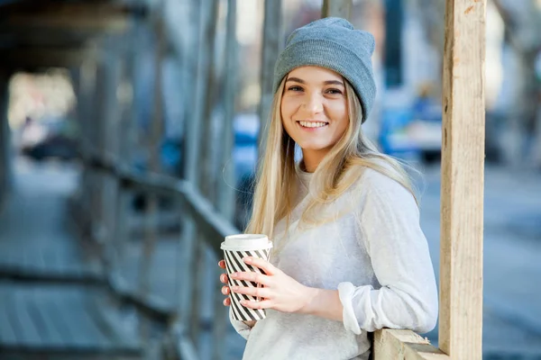 Beautiful woman holding paper coffee cup in the cityYoung stylish woman drinking coffee to go in a city street