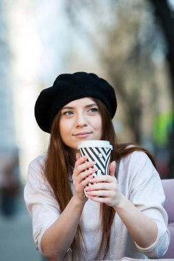 Açık havada moda portre gitmek için kahve içme genç güzel kız. Holding bir gülümseyen kız portresi yakından açık havada kahve fincanı götürün.