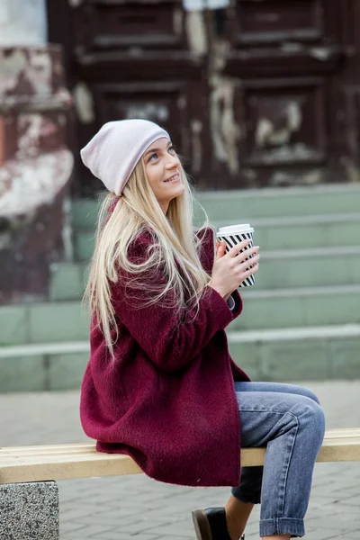 Gorgeous young woman with cup of coffee in city street. Coffee break. Coffee to go.Stylish hipster girl drinking coffee in street.