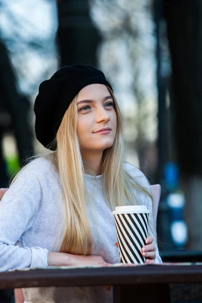 Gorgeous young woman with cup of coffee in city street. Coffee break. Coffee to go.Stylish hipster girl drinking coffee in street.