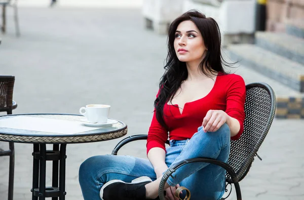 Gorgeous young woman with cup of coffee in city street. Coffee break. Stylish hipster girl drinking coffee in street.Outdoors fashion portrait of young beautiful girl drinking coffee.