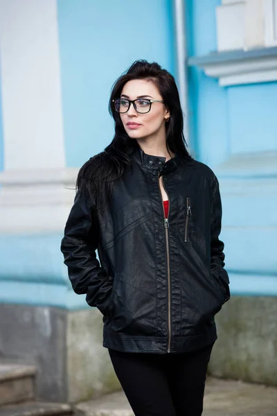 Beautiful girl with wavy hair in black leather jacket. Portrait of cute young business woman outdoor