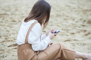 Kız dışarıda cep telefonuna mesaj atıyor. Telefonu olan kız. Telefonunda mutlu bir kadın metin sms mesajı Portresi.