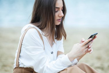 Kız dışarıda cep telefonuna mesaj atıyor. Telefonu olan kız. Telefonunda mutlu bir kadın metin sms mesajı Portresi.