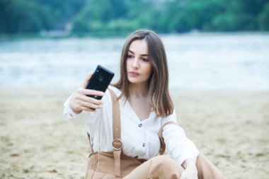 Kız dışarıda cep telefonuna mesaj atıyor. Telefonu olan kız. Telefonunda mutlu bir kadın metin sms mesajı Portresi.