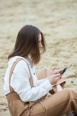 Kız dışarıda cep telefonuna mesaj atıyor. Telefonu olan kız. Telefonunda mutlu bir kadın metin sms mesajı Portresi.