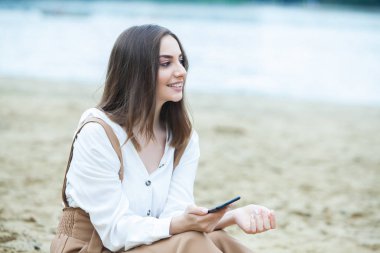 Kız dışarıda cep telefonuna mesaj atıyor. Telefonu olan kız. Telefonunda mutlu bir kadın metin sms mesajı Portresi.