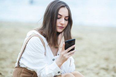 Kız dışarıda cep telefonuna mesaj atıyor. Telefonu olan kız. Telefonunda mutlu bir kadın metin sms mesajı Portresi.